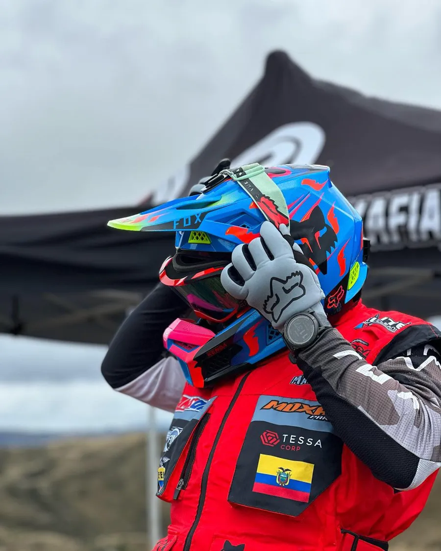 Piloto de motocross con casco y bandera de Ecuador